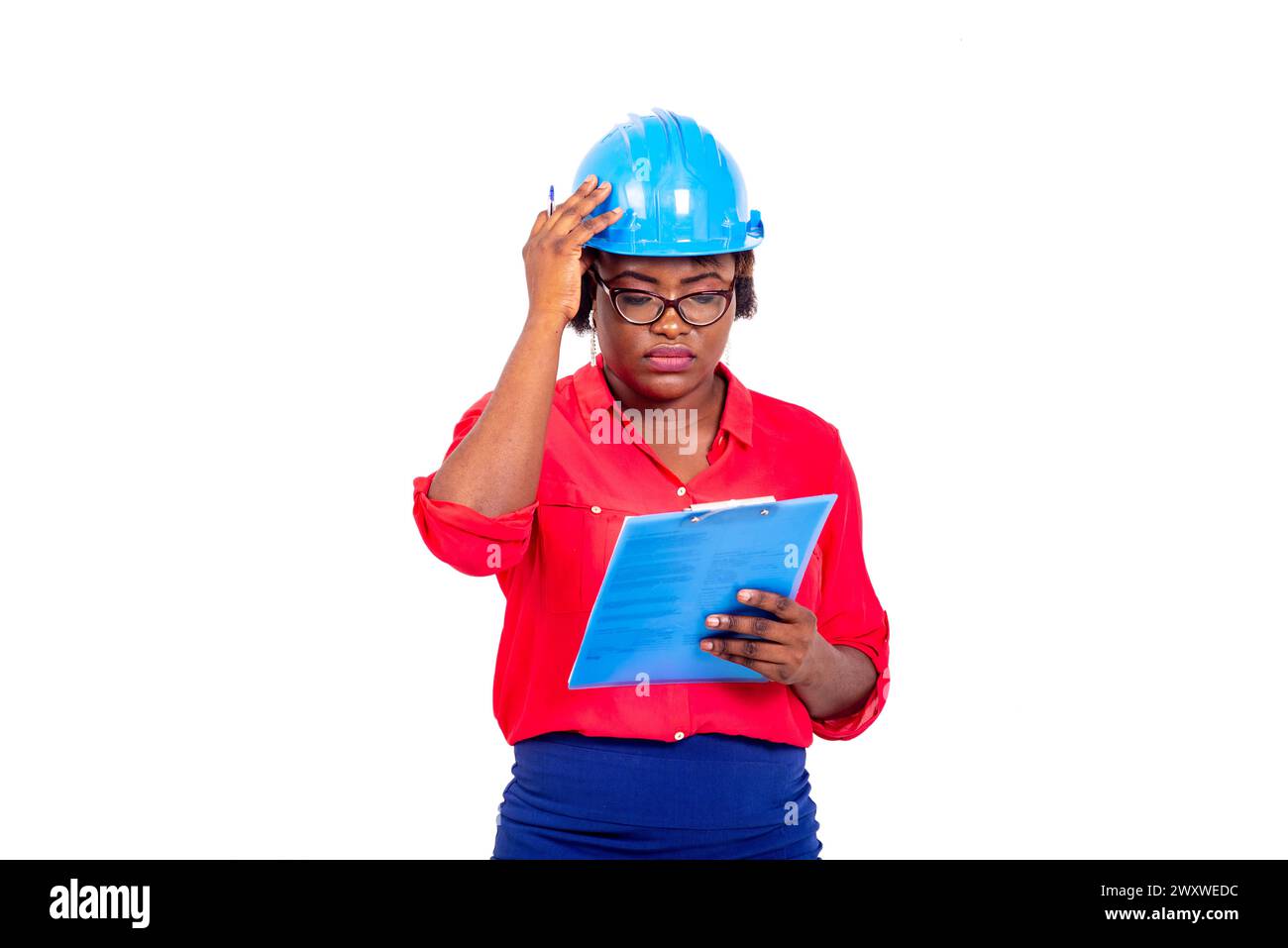 beautiful female engineer wearing blue safety helmet reading notes on clipboard. Stock Photo