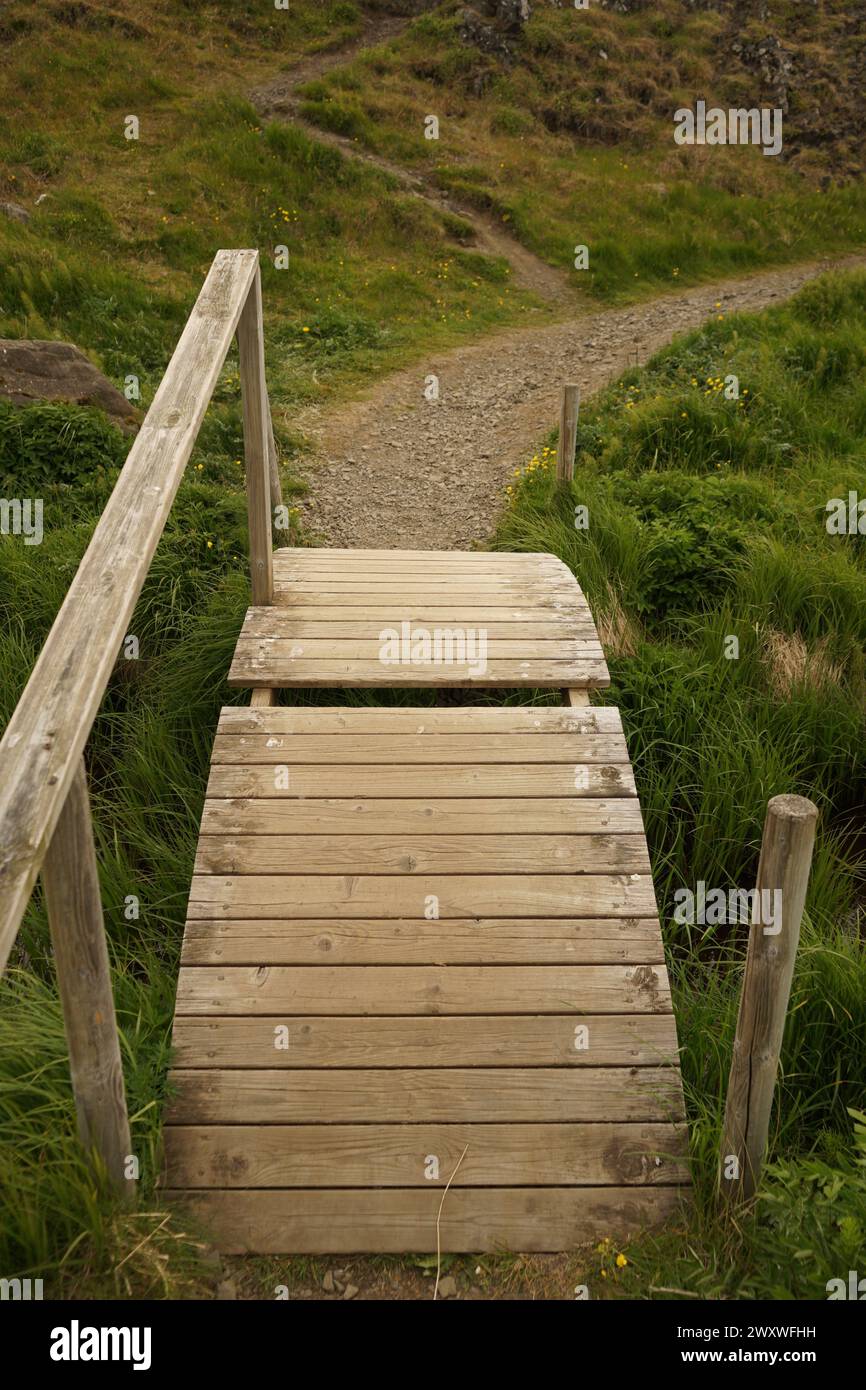 Small wooden bridge over a stream next to Fossarétt Waterfall in Iceland Stock Photo