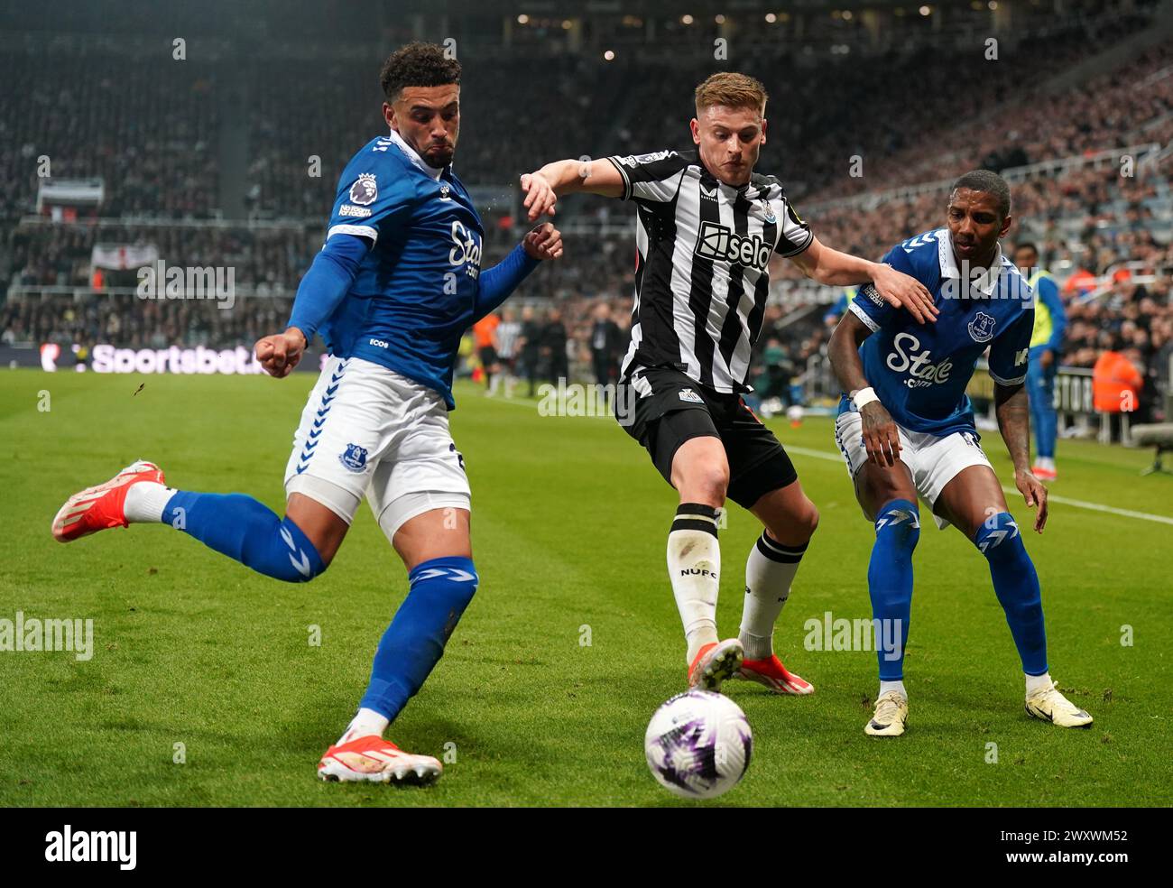 Everton's Ben Godfrey, Newcastle United's Harvey Barnes (left) and Everton's Ashley Young battle for the ball during the Premier League match at St. James' Park, Newcastle upon Tyne. Picture date: Tuesday April 2, 2024. Stock Photo