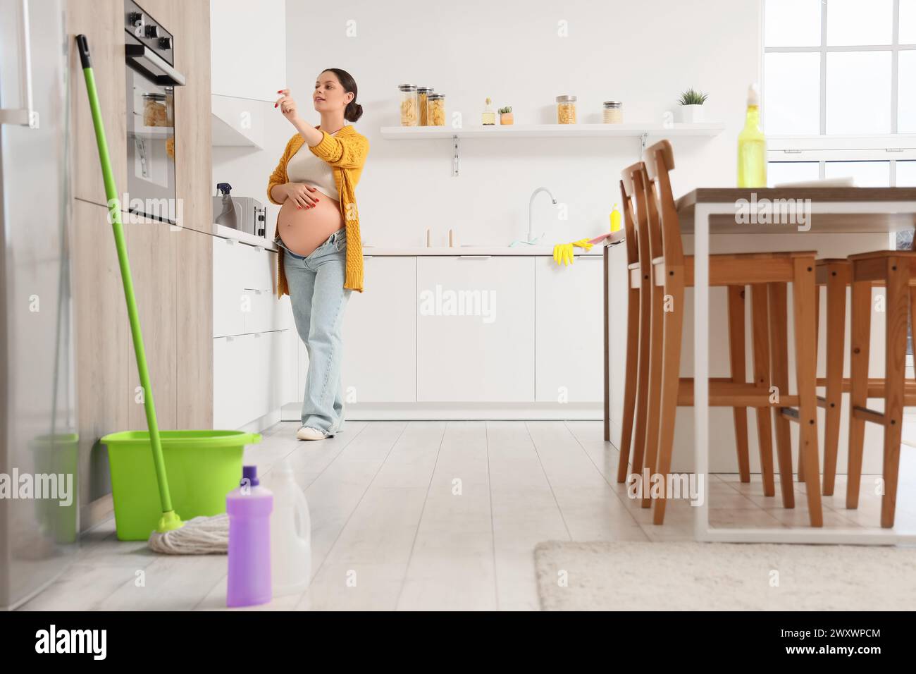 Young pregnant woman cleaning cupboard in kitchen Stock Photo