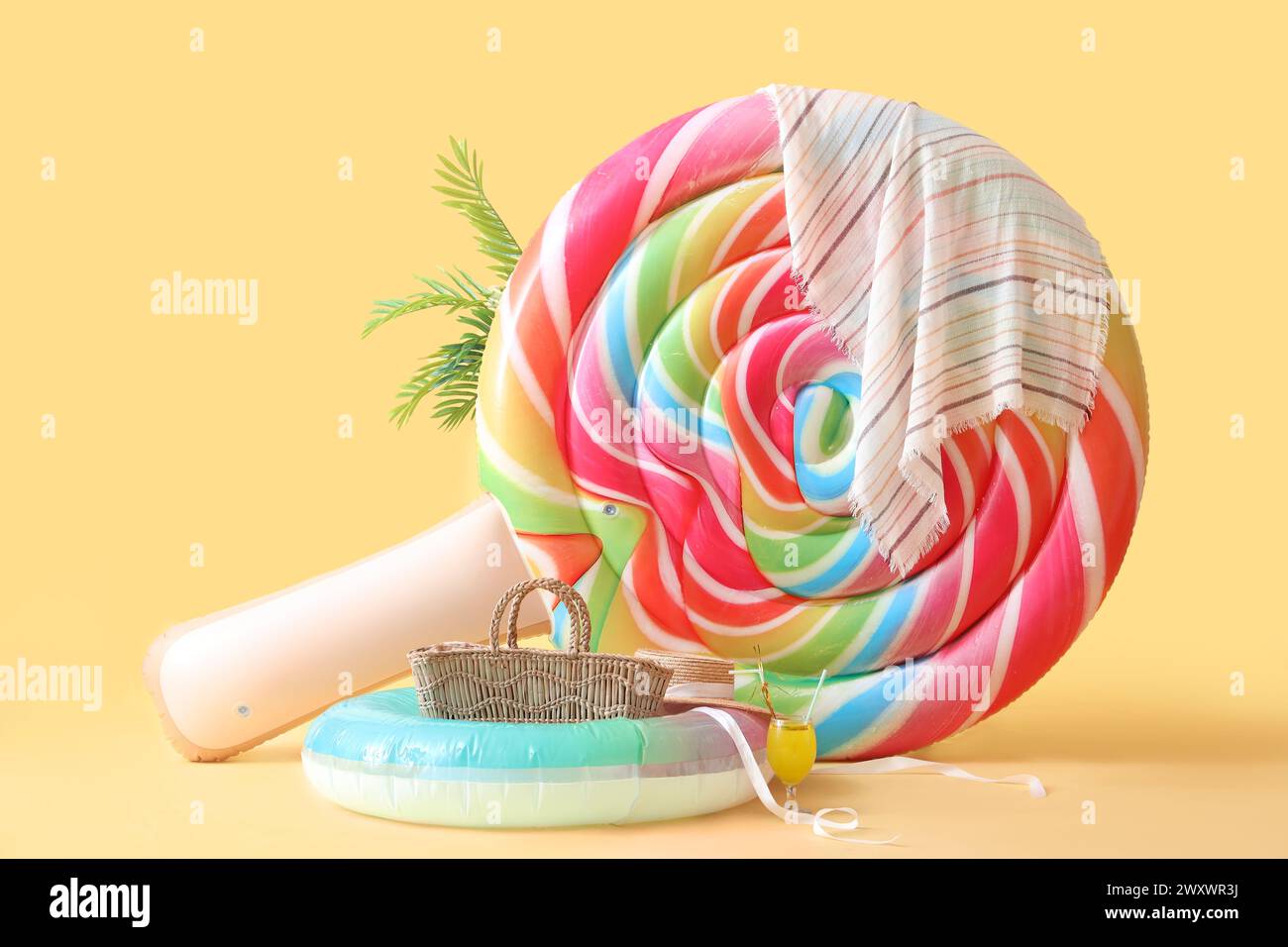 Swimming mattress in shape of candy with inflatable rings and straw bag on yellow background Stock Photo