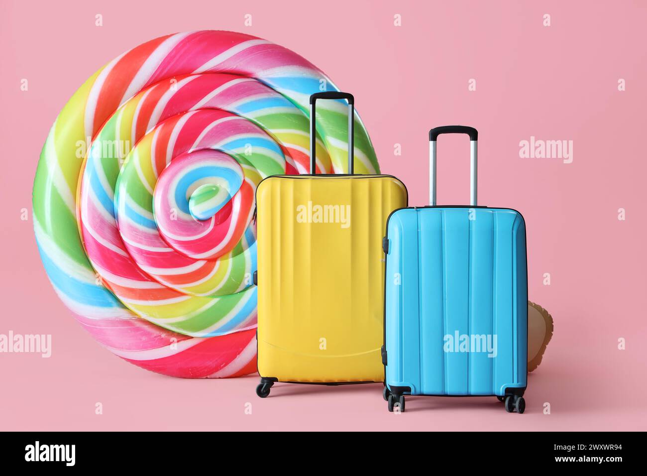 Inflatable mattress in shape of candy and suitcases on pink background Stock Photo