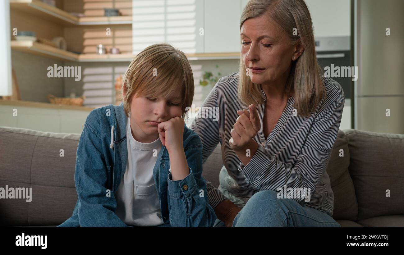 Strict angry elderly senior Caucasian woman grandmother punishing disobedient lazy offended grandson at home scolding grandchild kid boy due to bad Stock Photo