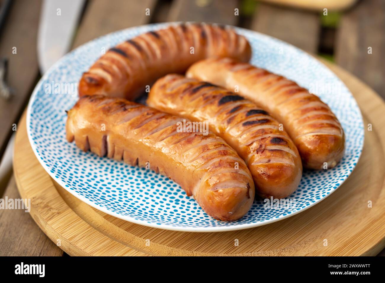 plate of freshly grilled sausages on picnic table in garden party Stock Photo