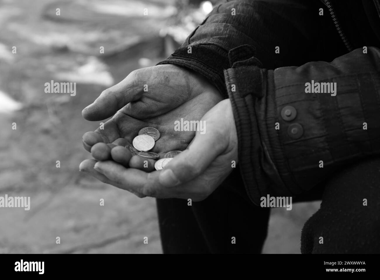 Poor homeless man holding coins outdoors, closeup. Black and white effect Stock Photo