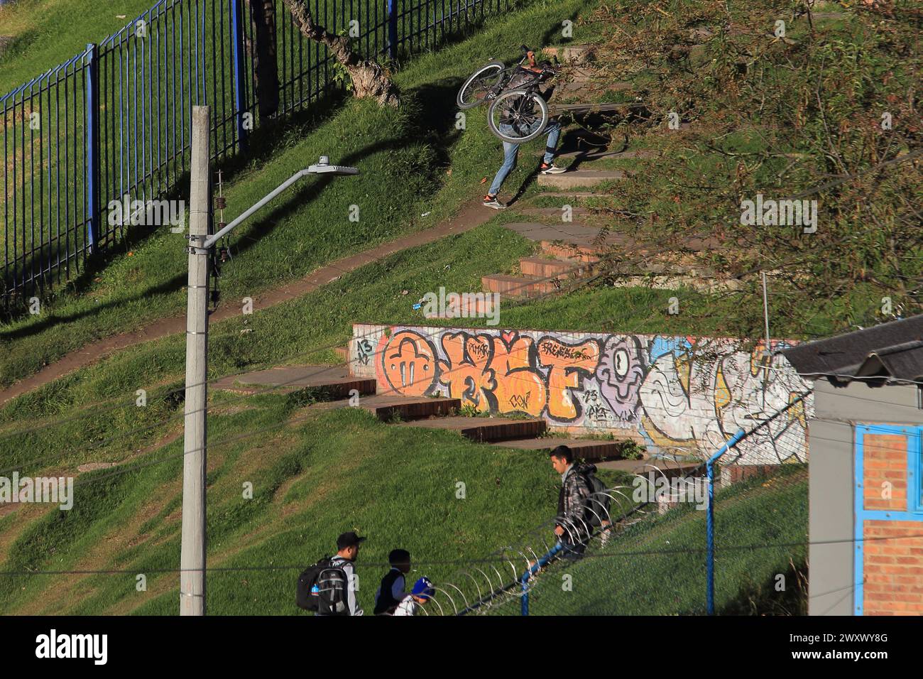 Bogota, Colombia, 24-01-2024. A cyclist climbs his bike loads his bike on his back, while climbing a hill to reach his home in a neighborhood of Bogot Stock Photo