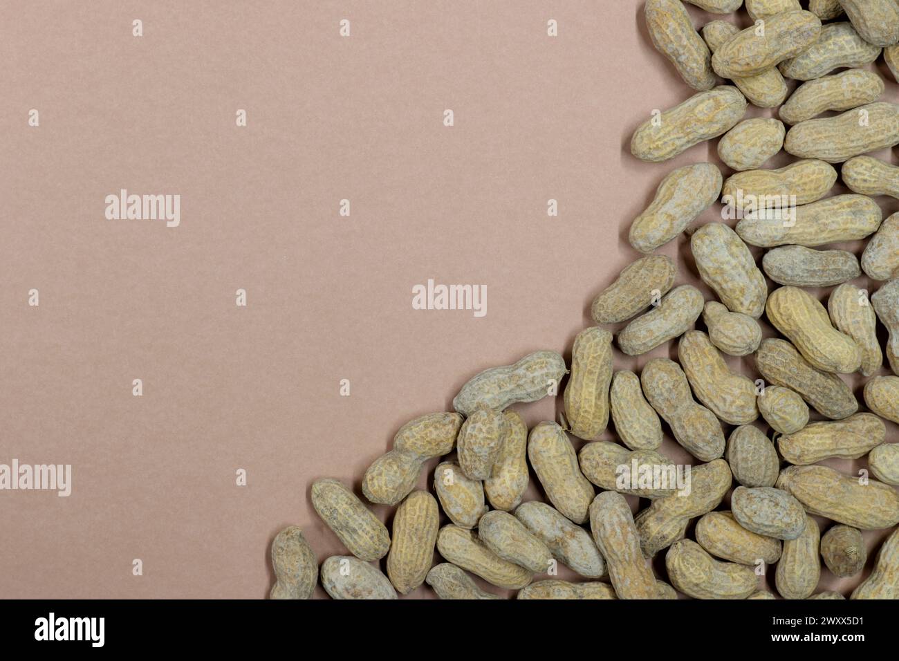 Unshelled peanuts scattered on cardstock background with copy space