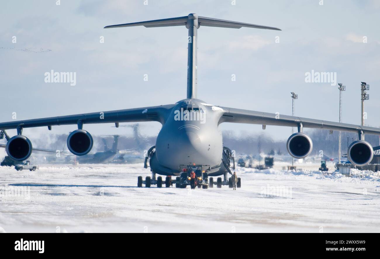 Team Dover aircraft maintenance personnel tow a C-5M Super Galaxy down the flight line Jan. 3, 2014, at Dover Air Force Base, Del. The tow team crew pushed the aircraft out of the wash rack hangar after the snow storm passed. (U.S. Air Force photo/Roland Balik) Stock Photo