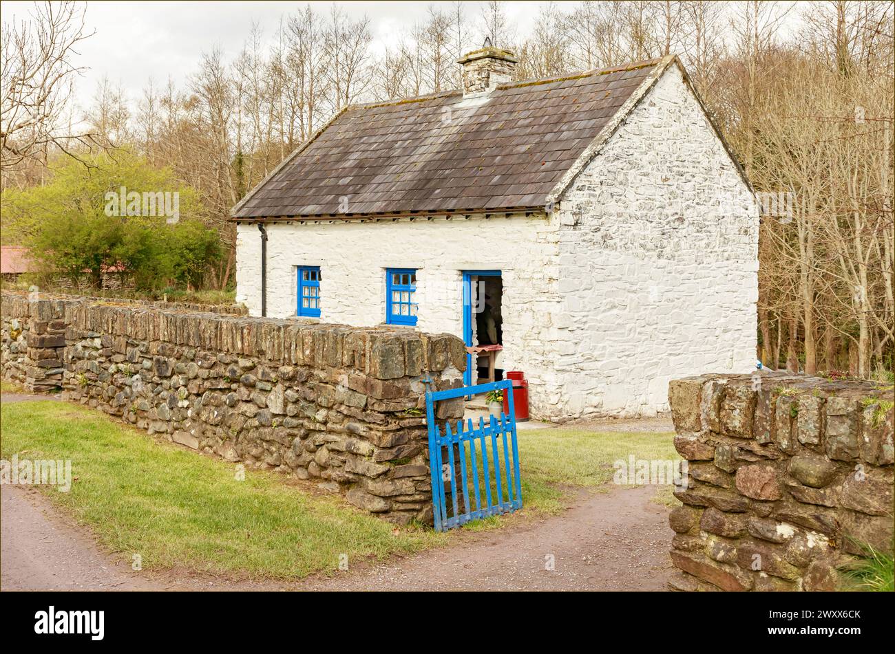 Traditional white and blue painted Irish cottage with a stone wall and blue painted gate Stock Photo
