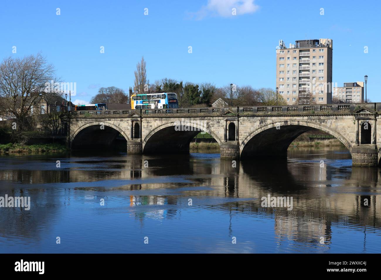 Stagecoach buses crossing historic Skerton Bridge over River Lune in Lancaster, Lancashire, England at high tide on 30th March 2024. Stock Photo
