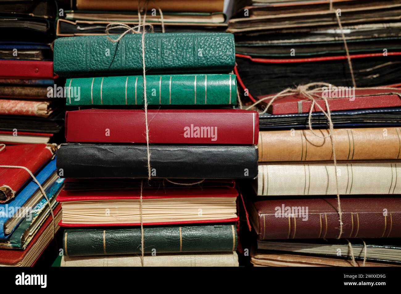 A collection of old and worn books bound with twine, stacked in a haphazard fashion. Stock Photo