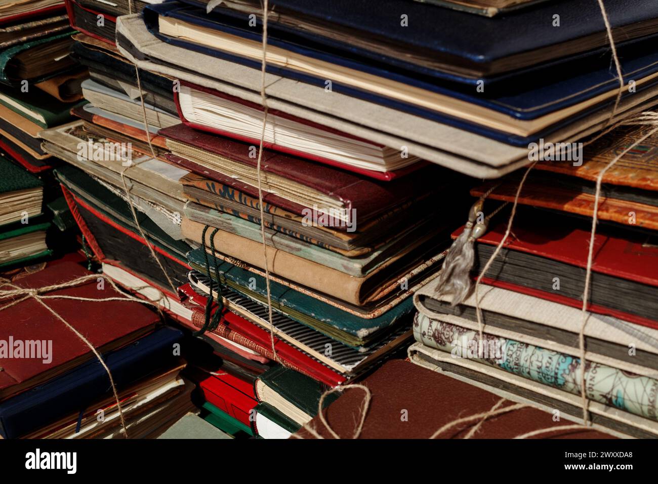 A collection of old and worn books bound with twine, stacked in a haphazard fashion. Stock Photo
