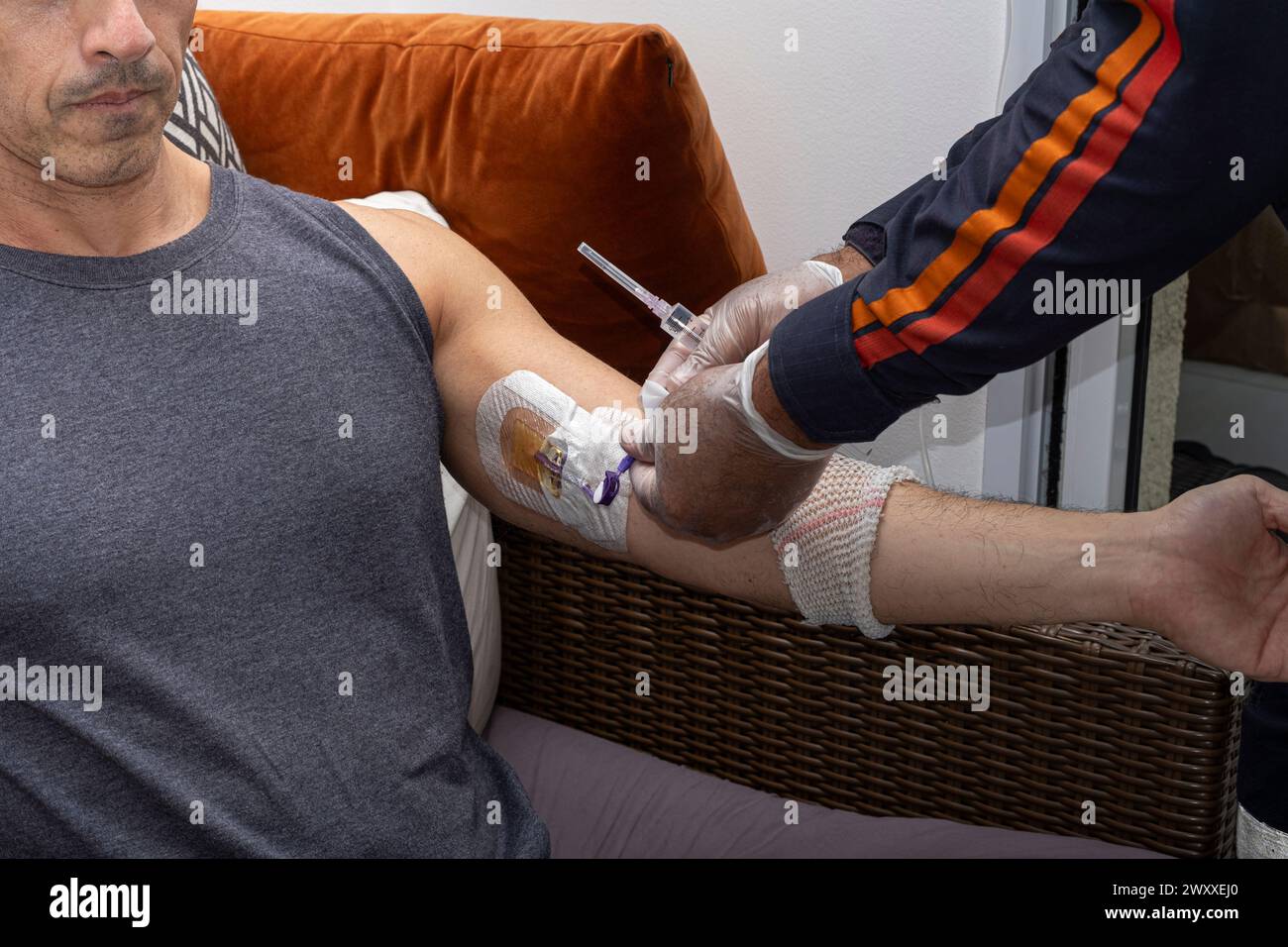 Nurse, with protective gloves, cleaning the nozzle accessing the catheter. Stock Photo