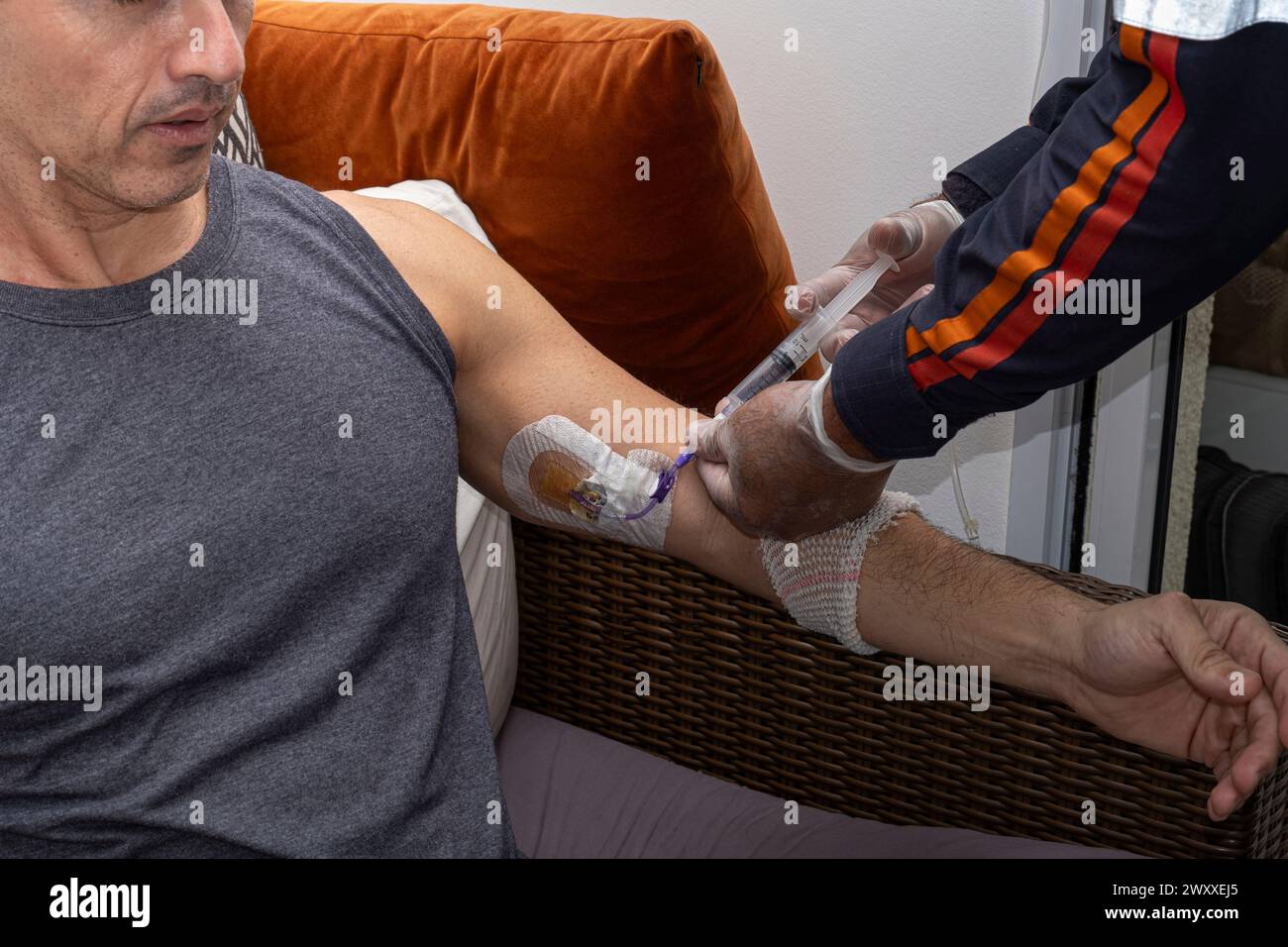 Nurse, with protective gloves, applying serum to clean the catheter. Stock Photo