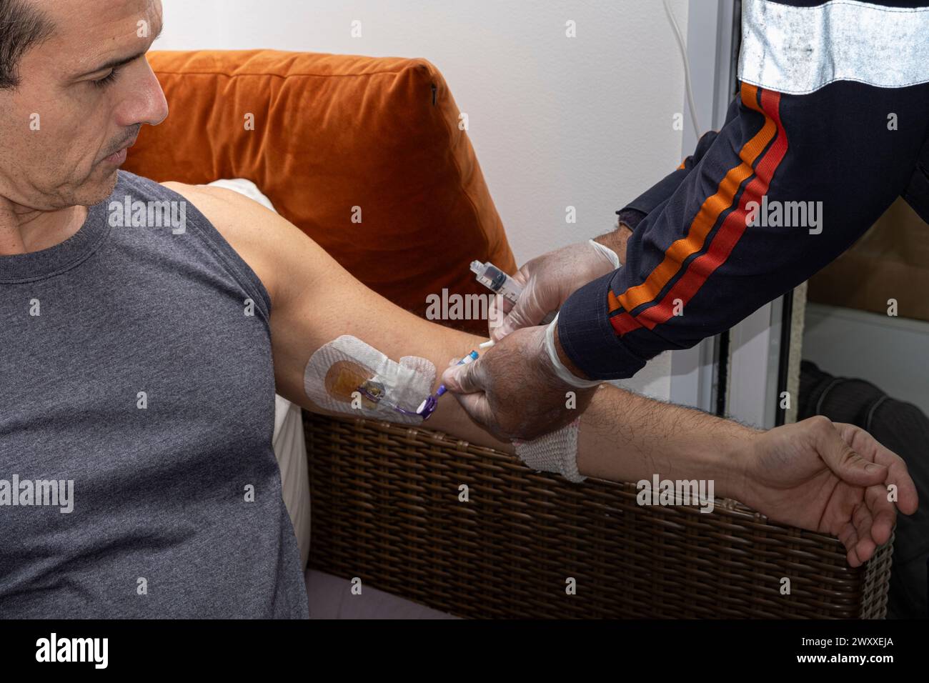 Nurse, with protective gloves, placing the serum equipment on the catheter to give the anti-inflammatory. Stock Photo