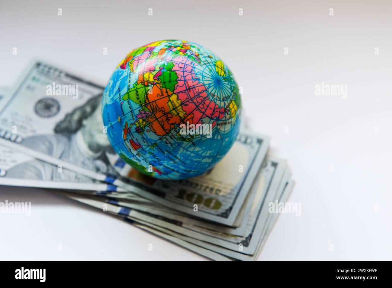 toy globe on a pile of one hundred dollar bills Stock Photo
