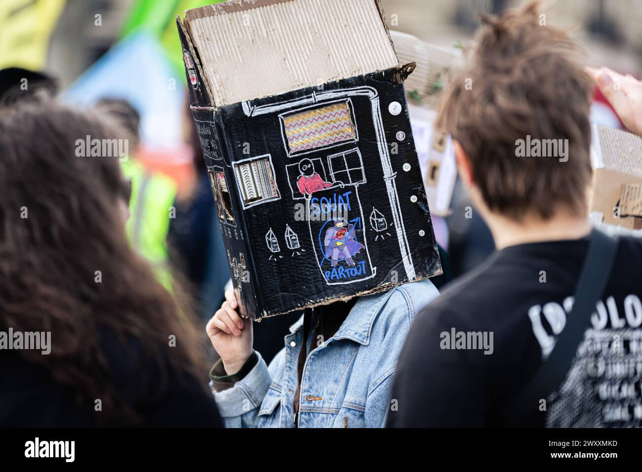 A protester is seen with a paper house on his head that says 'Squat everywhere' during the demonstration against housing crisis. Thousands of people attended the demonstration for the right to housing, in Paris. The movement organized by the association 'DAL' Droit Au Logement (Right to Housing), focused on denouncing the start of evictions that will begin at the beginning of April. It was also demanded a reduction in rents, the requisition of empty houses for rent, accommodation for all inhabitants and an end to real estate speculation. Stock Photo