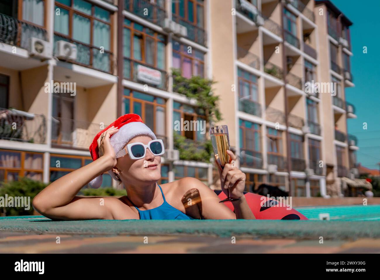 Woman pool Santa hat. A happy woman in a blue bikini, a red and white ...