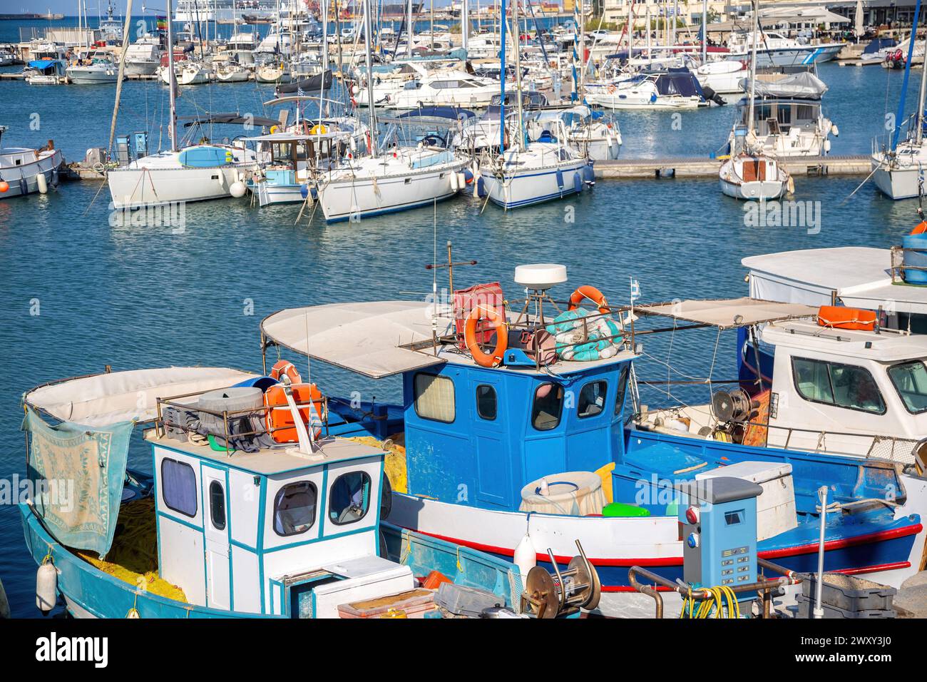 Crete island, destination Greece. Moored vessel with mast and fishing boat at Heraklion old Venetian harbor, calm sea water, blue sky background. Stock Photo