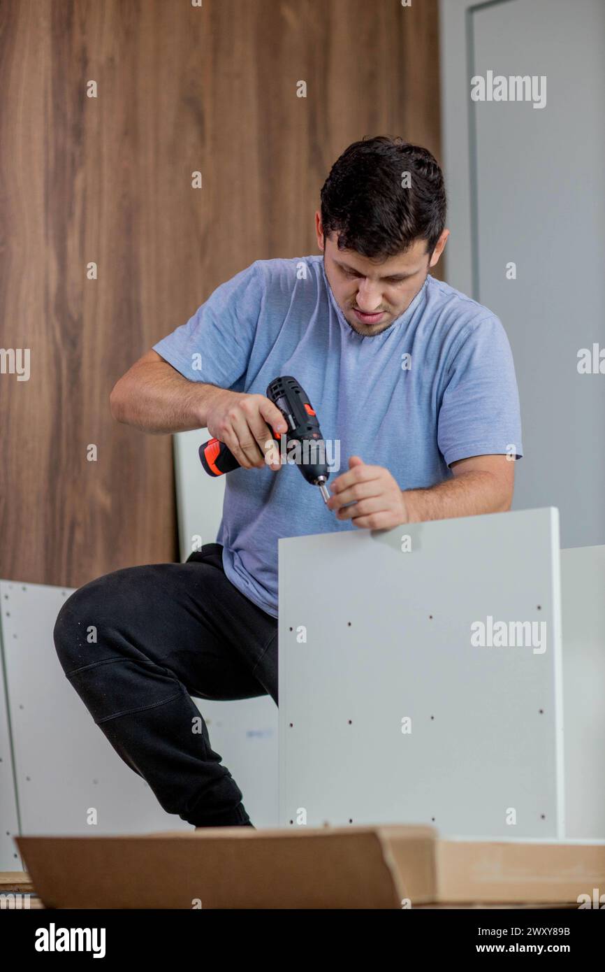 Man assembling furniture by using cordless screwdriver. Stock Photo