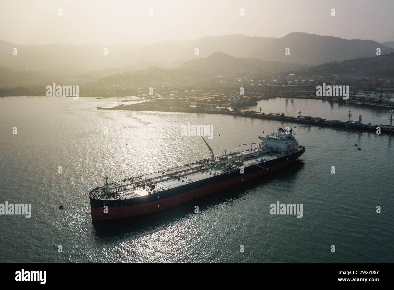 Tanker moored at oil terminal, intricate part of global petro resource trade, aerial view from drone. Key hub in industry logistics and distribution. Essential in the chain of energy supply and commerce. Stock Photo