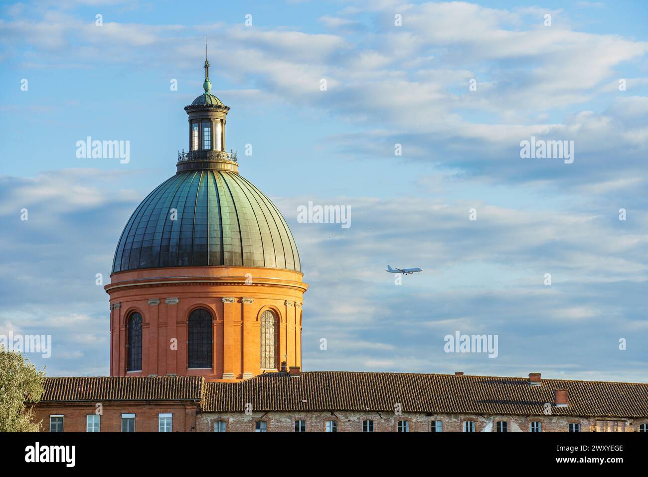 A passenger plane flies over the city of Toulouse in France with its iconic dome Stock Photo