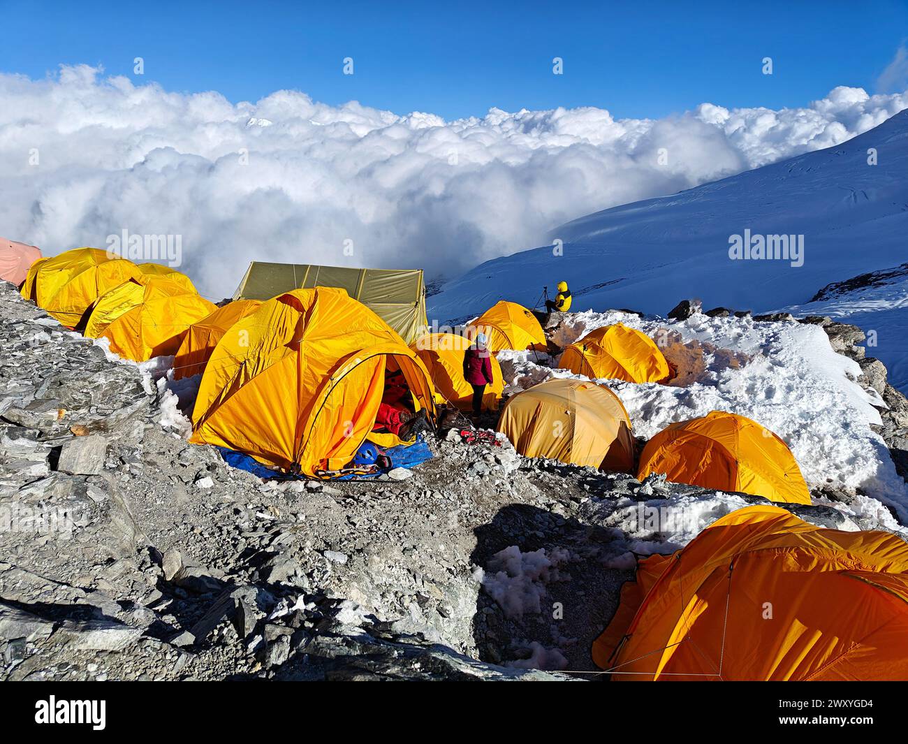Mountaineering camp on snowy ridge, yellow tents, blue sky, clouds ...
