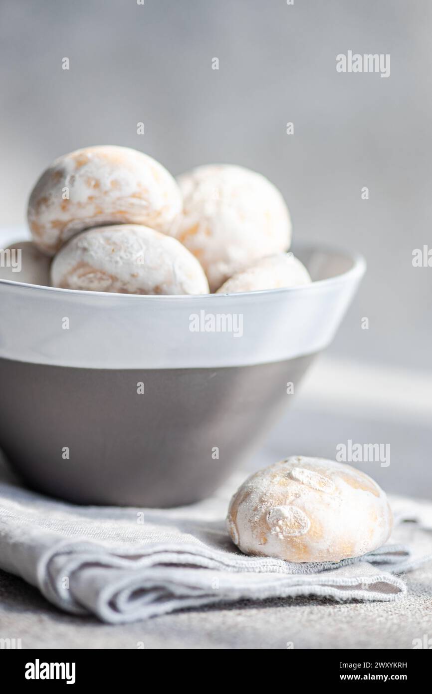 A close-up of powdered gingerbread cookies nestled in a modern ceramic bowl, presented on a soft fabric surface with a neutral backdrop Stock Photo