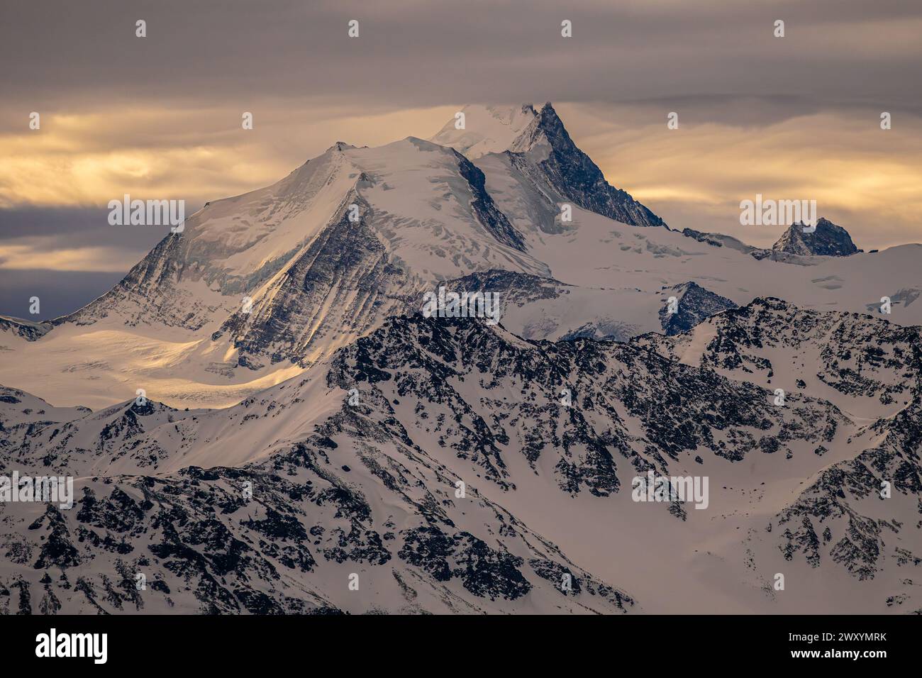 The warm light of sunset bathes a majestic alpine mountain ...