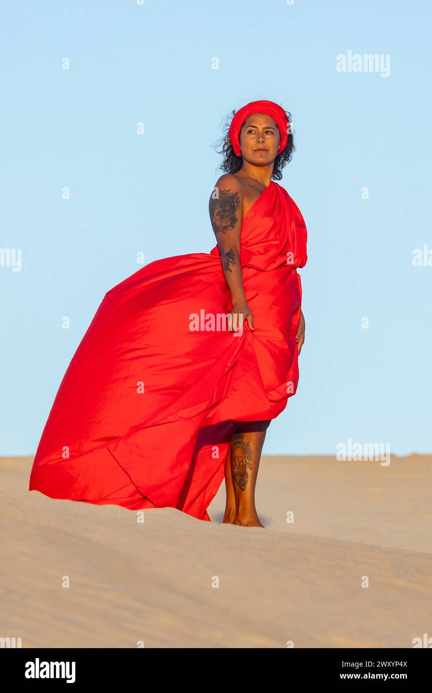 An enigmatic woman clad in a flowing red dress stands majestically on ...