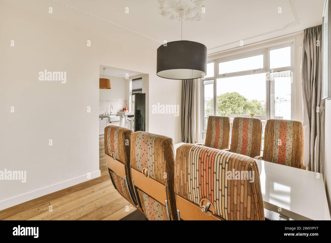 A cozy modern dining room featuring patterned chairs and a dark hanging ...