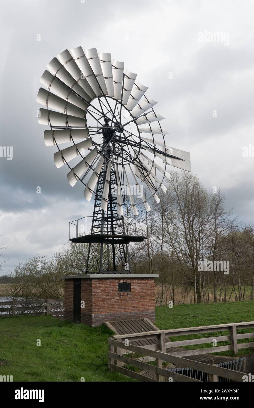 American windmill on a dike in the Netherlands for regulating the waterlevel in a polder Stock Photo