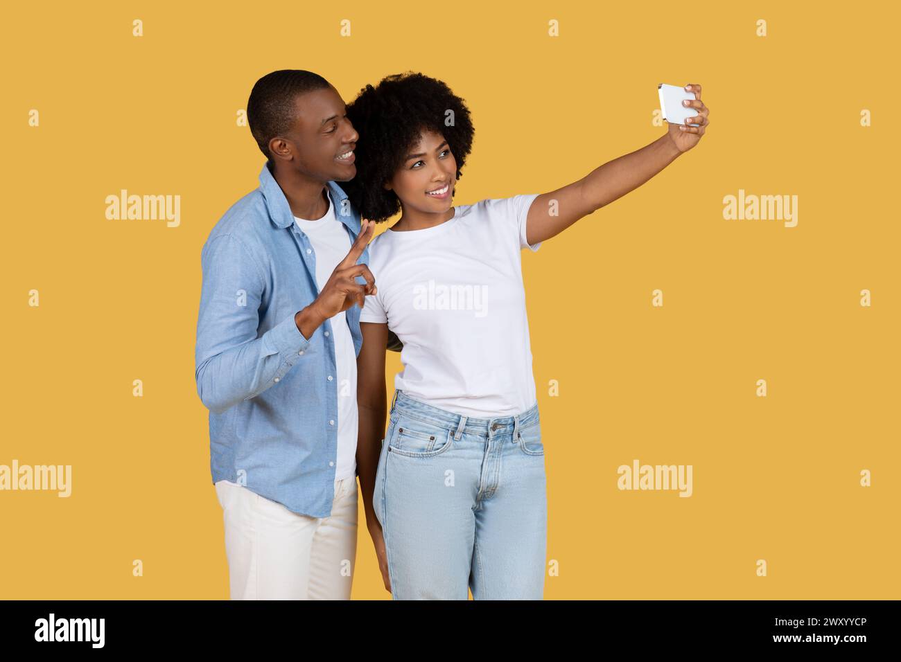 Couple taking selfie with smartphone on yellow Stock Photo
