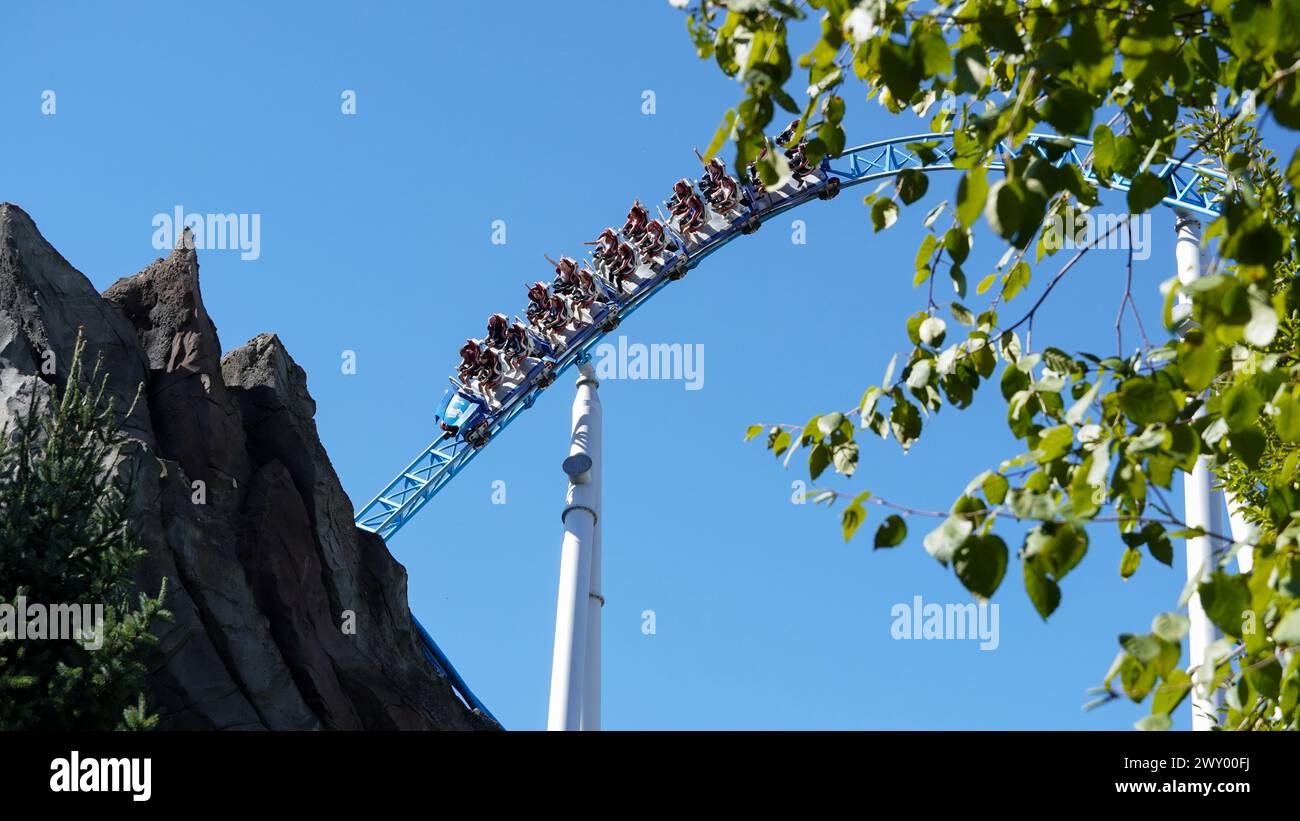 Young people have fun on the 'Blue Fire' rollercoaster at the 'Europa-Park' theme park. They scream, laugh and enjoy their summer holiday in the beaut Stock Photo