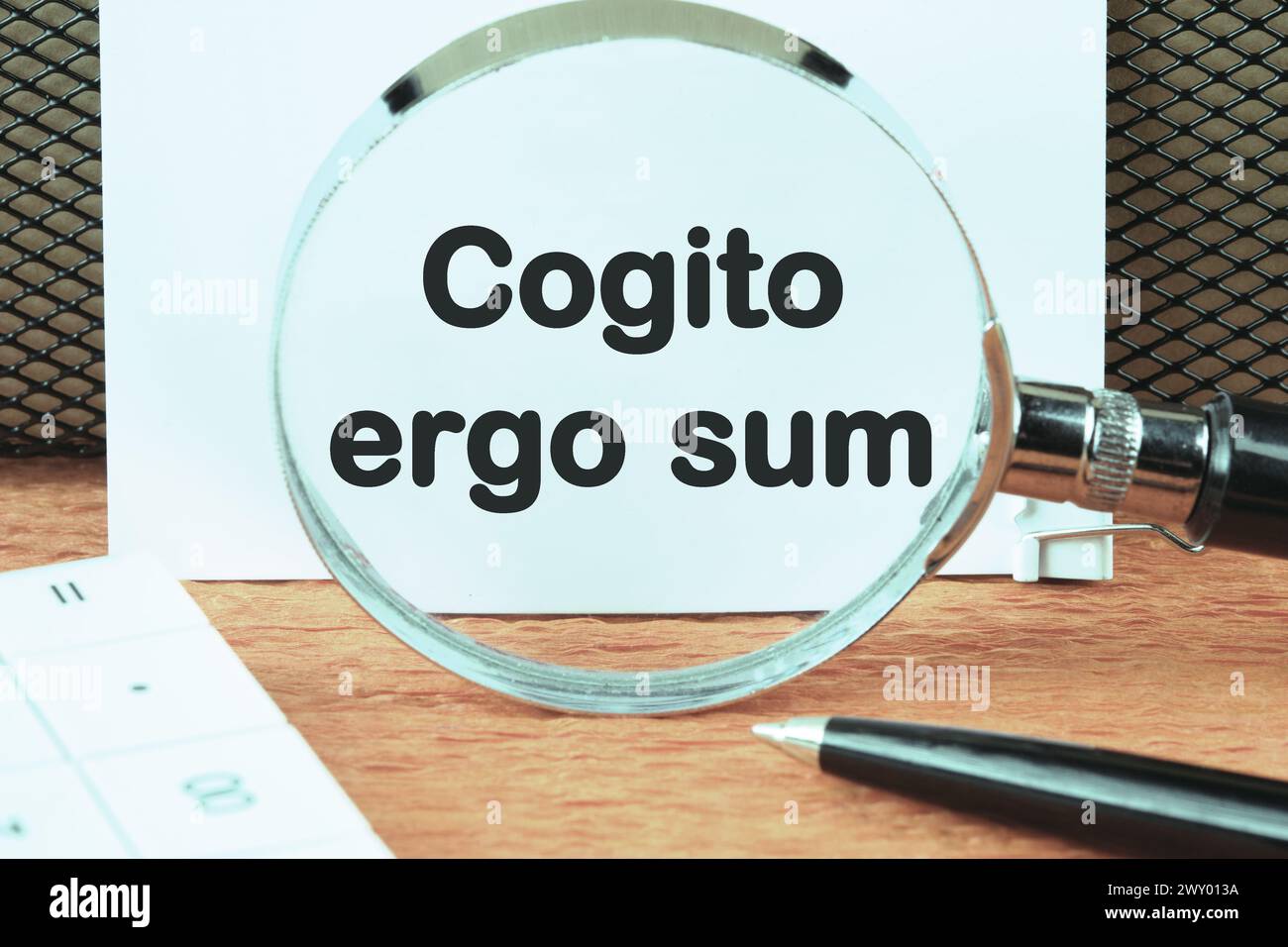 The words Cogito Ergo Sum or I think Therefore I Am an inscription was found using a magnifying glass on a white sheet. Concept photo Stock Photo