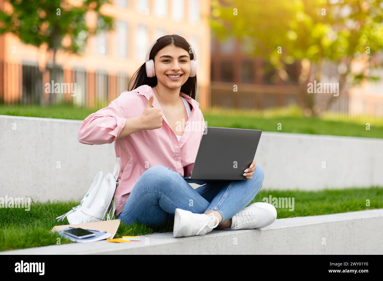 Girl giving thumbs up with laptop outside Stock Photo - Alamy