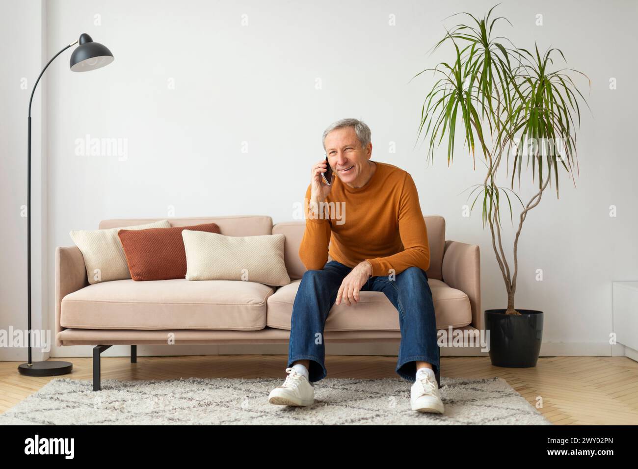 Man sitting on couch talking on phone Stock Photo