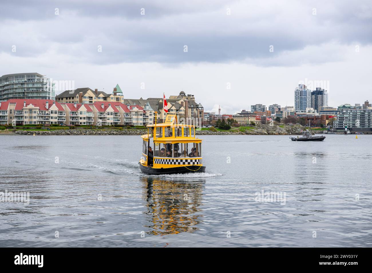 A yellow boat on water with urban skyline in the distance in Victoria ...