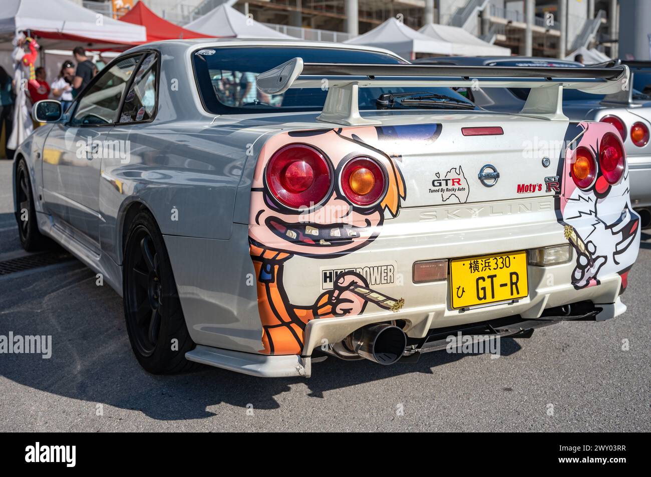 Rear view of a tenth generation Nissan Skyline GT R34 with some vinyls of Doraemon drawings at a Japanese sports car meet. Stock Photo