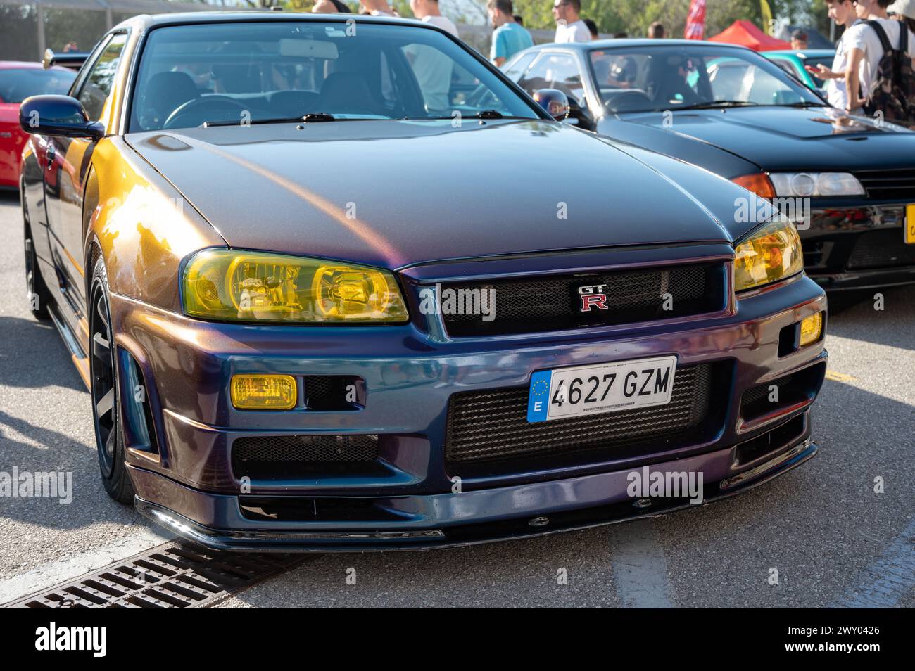 Front view of a tenth generation Nissan Skyline GT-R34 with a changing iridescent color at a Japanese sports car meet. Stock Photo