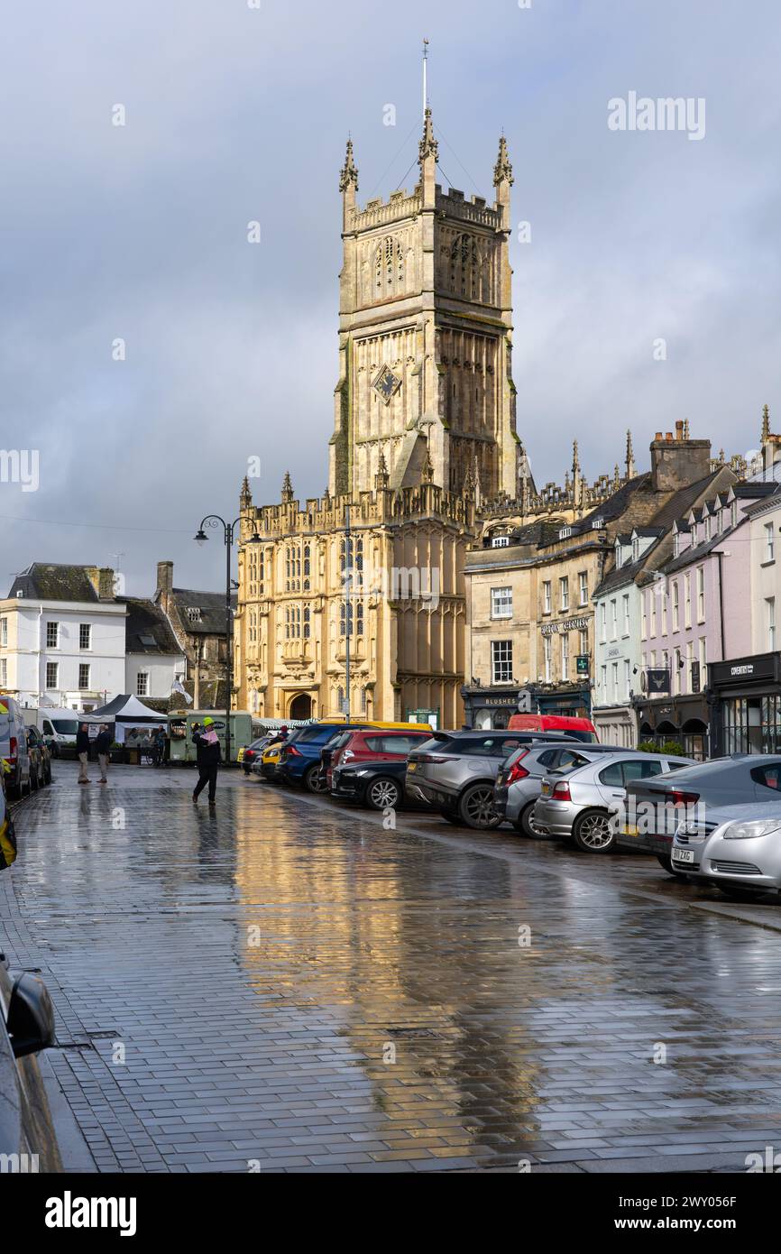 Grade I listed medieval St John the Baptist church and south porch, with perpendicular gothic architecture, reflected in puddles. Cirencester, UK Stock Photo