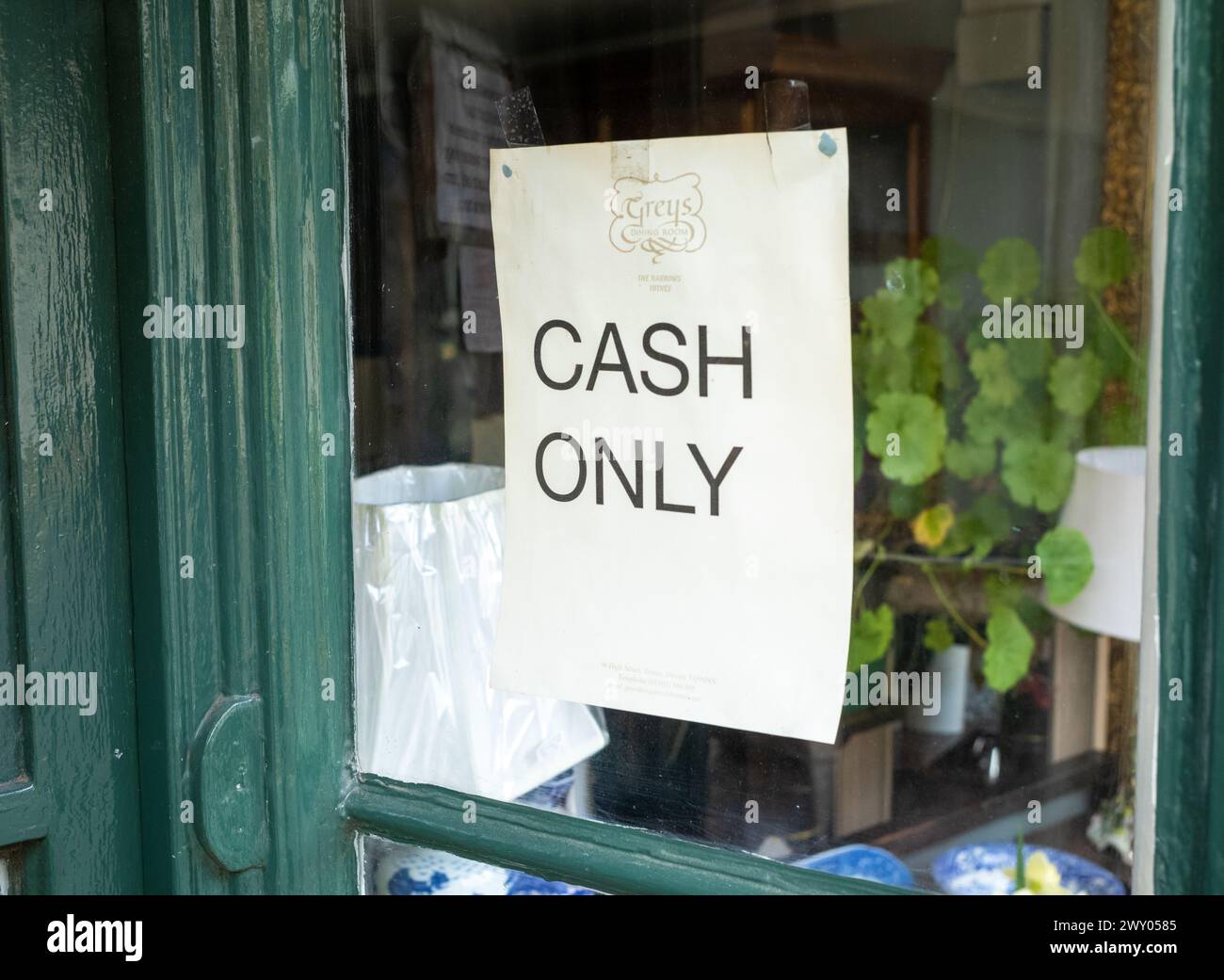 A sign in the window of a cafe advising customers they only accept cash, Totnes, Devon, UK. Stock Photo