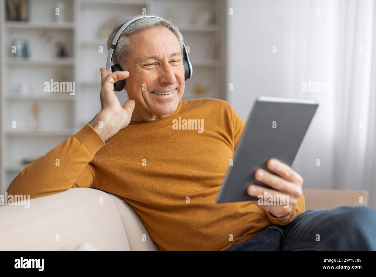 Happy senior man with headphones using tablet Stock Photo