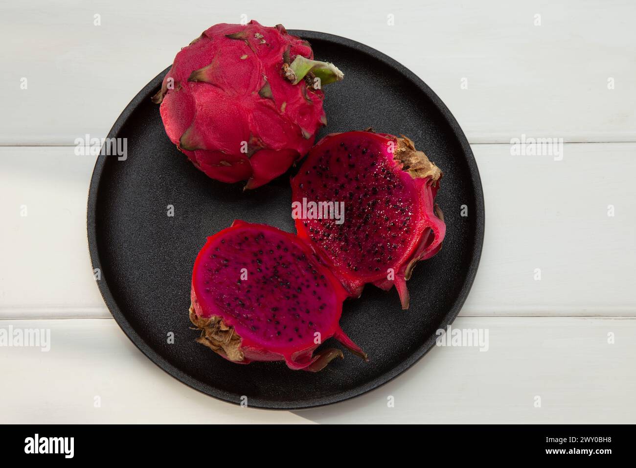 A Dragon fruit on black plate with white background Stock Photo