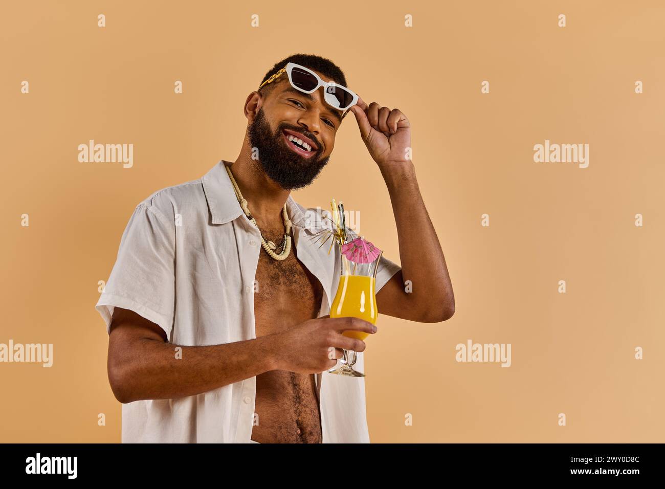 A stylish man shielded by trendy sunglasses holds a cool drink in his hand, exuding a relaxed and confident vibe as he enjoys his beverage. Stock Photo