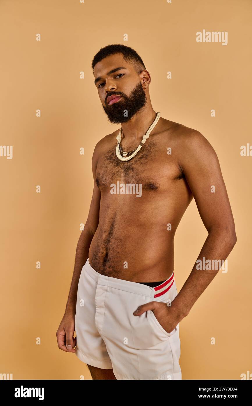 A man with a full beard stands confidently, sporting white shorts. His beard adds a rugged touch to his relaxed and casual outfit. Stock Photo