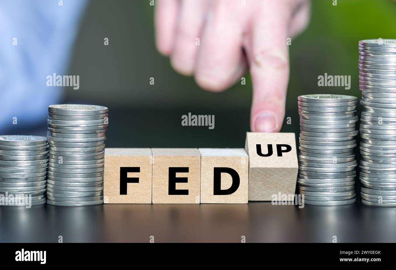 Hand turns wooden cube and changes the expression FED (Federal Reserve System) to 'fed up'. Stock Photo
