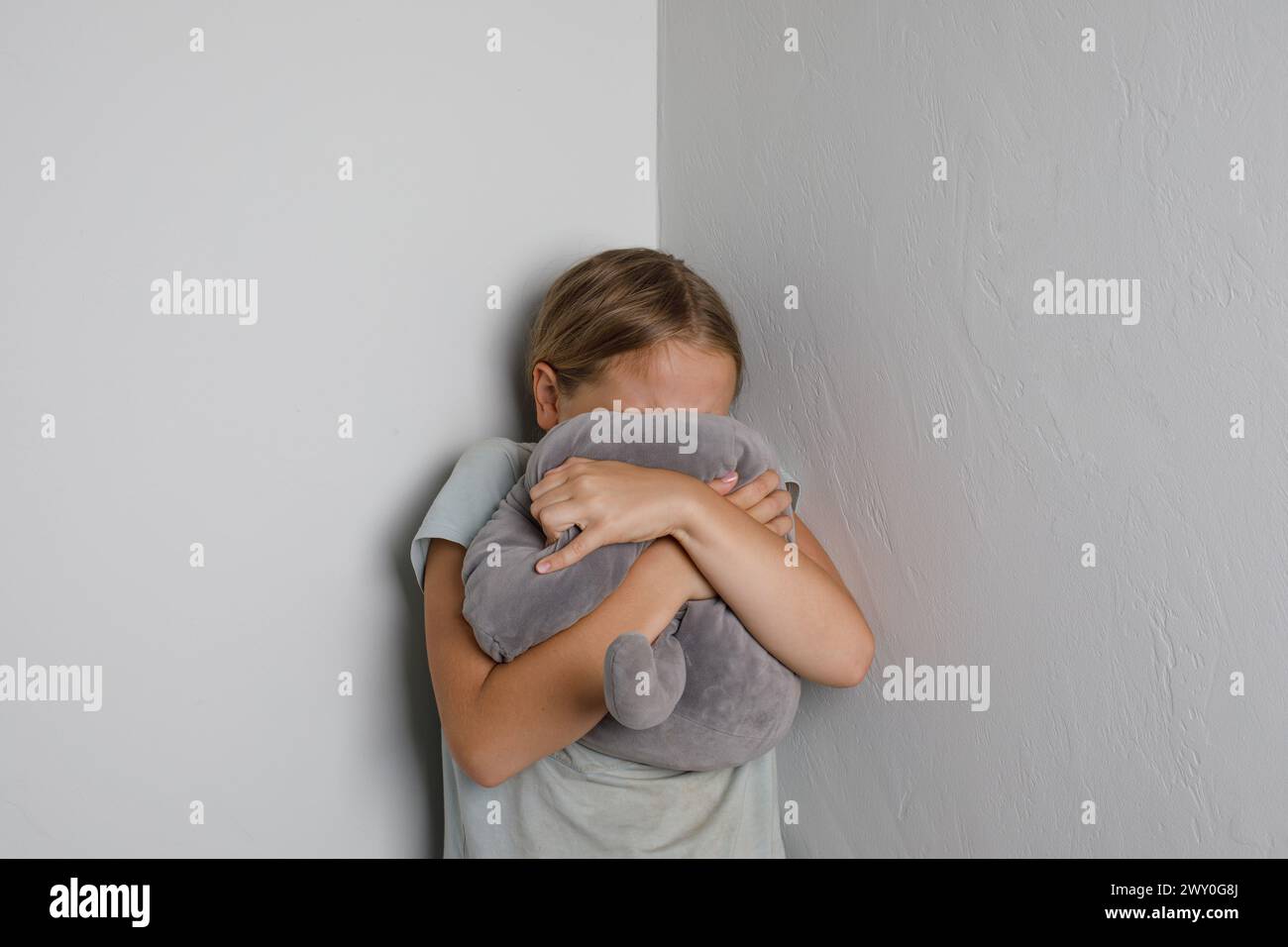 Young Girl Crying with Hands and Toy Covering Face at home Stock Photo