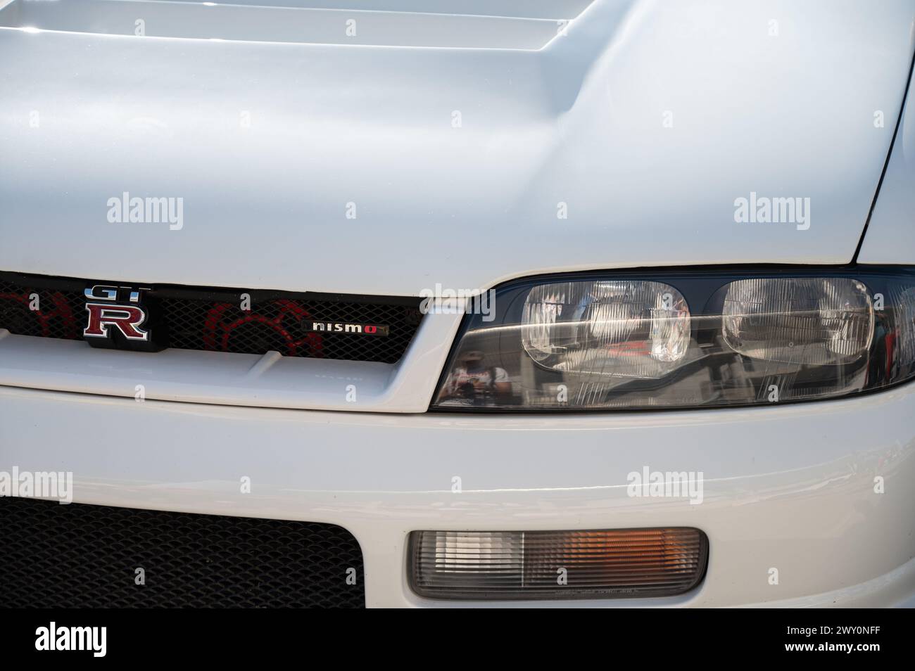 Front view of a white ninth-generation Nissan Skyline GT R33 at a Japanese sports car meet. Stock Photo