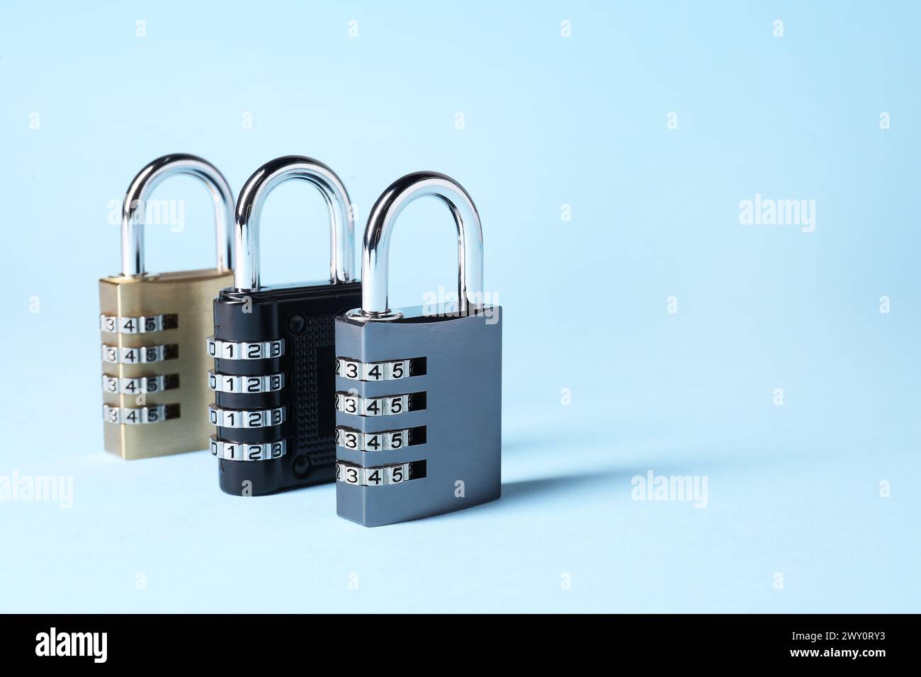 Steel combination padlocks on light blue background. Space for text Stock Photo